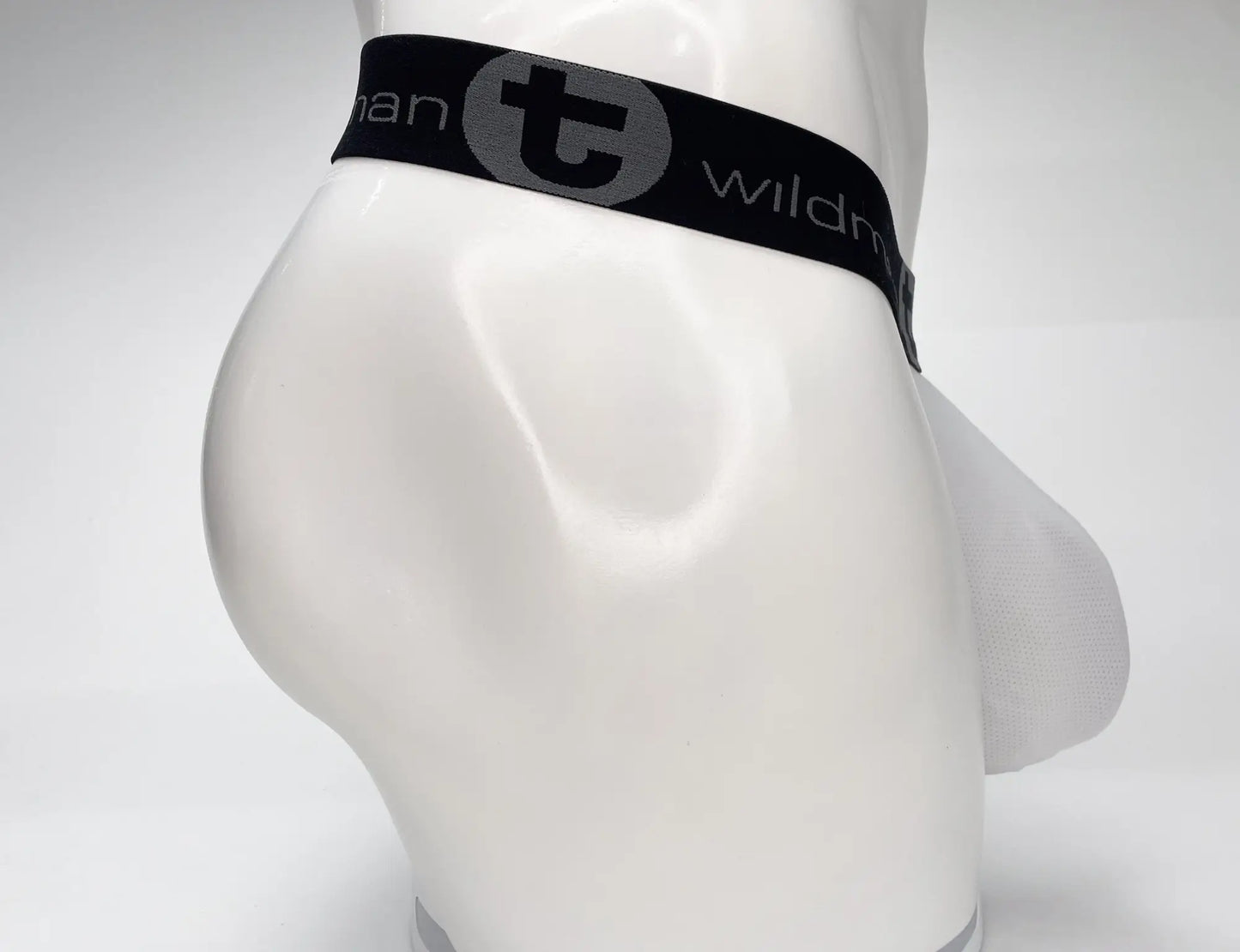 Black elastic waistband with gray wildman logo on white mesh monster cock strapless pouch on mannequin torso
