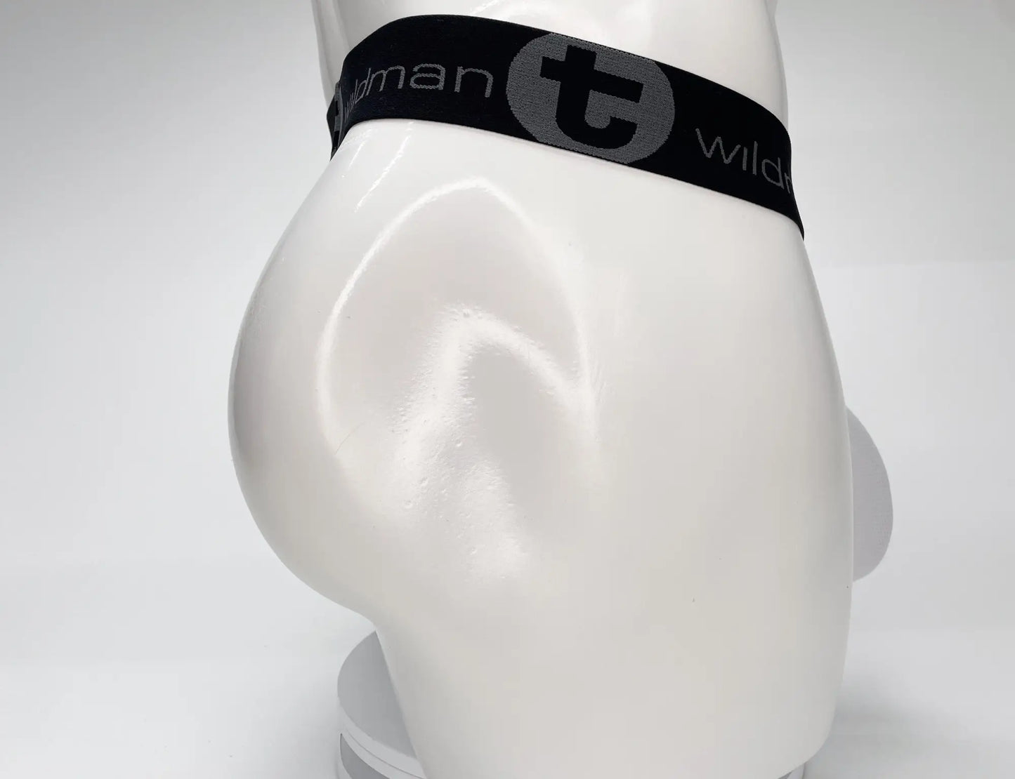 Black elastic waistband with gray t logo and wildman branding on white wildmant mesh monster cock strapless pouch