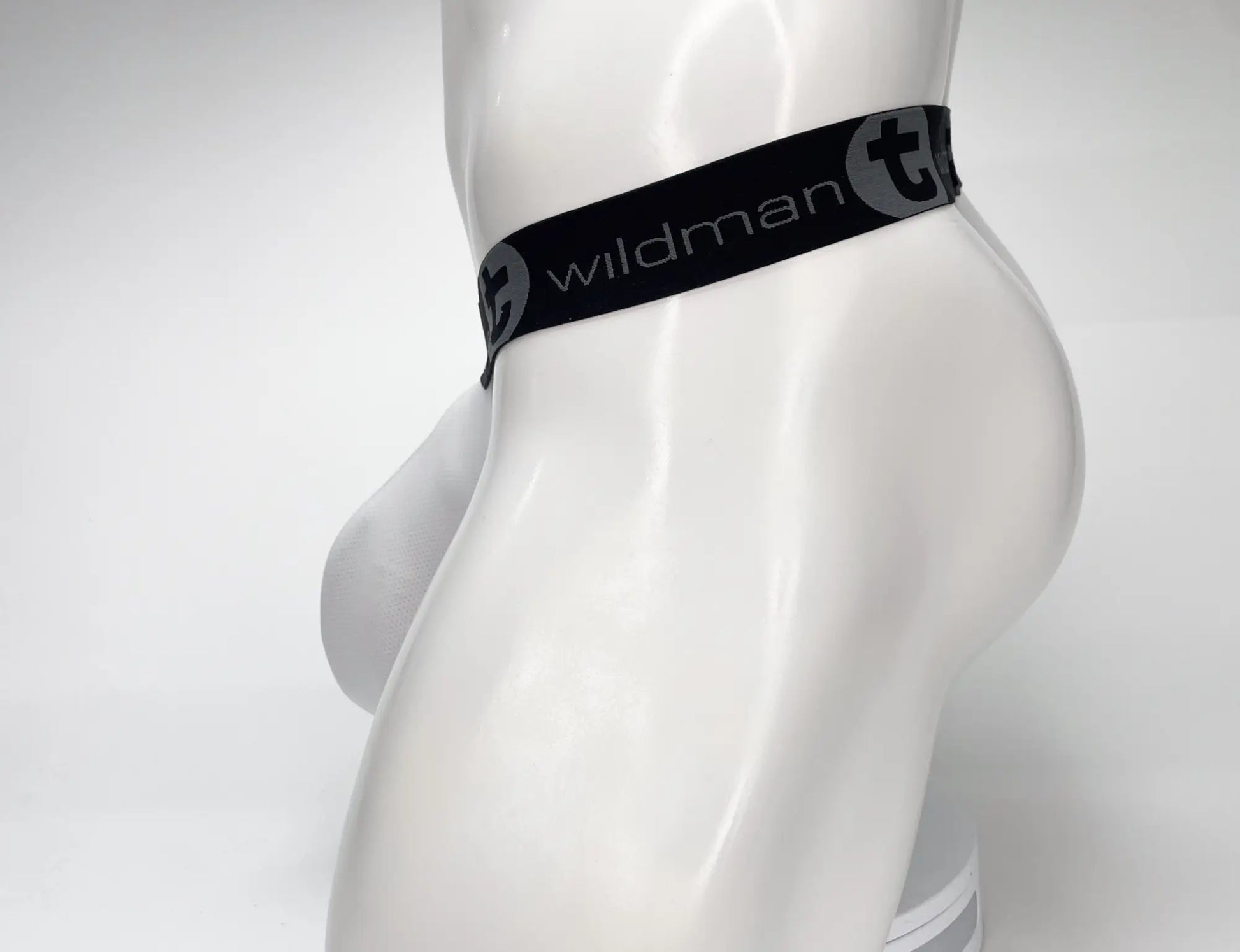 Black elastic waistband with white wildman branding and stylized t logo on wildmant mesh monster cock strapless pouch white displayed on mannequin