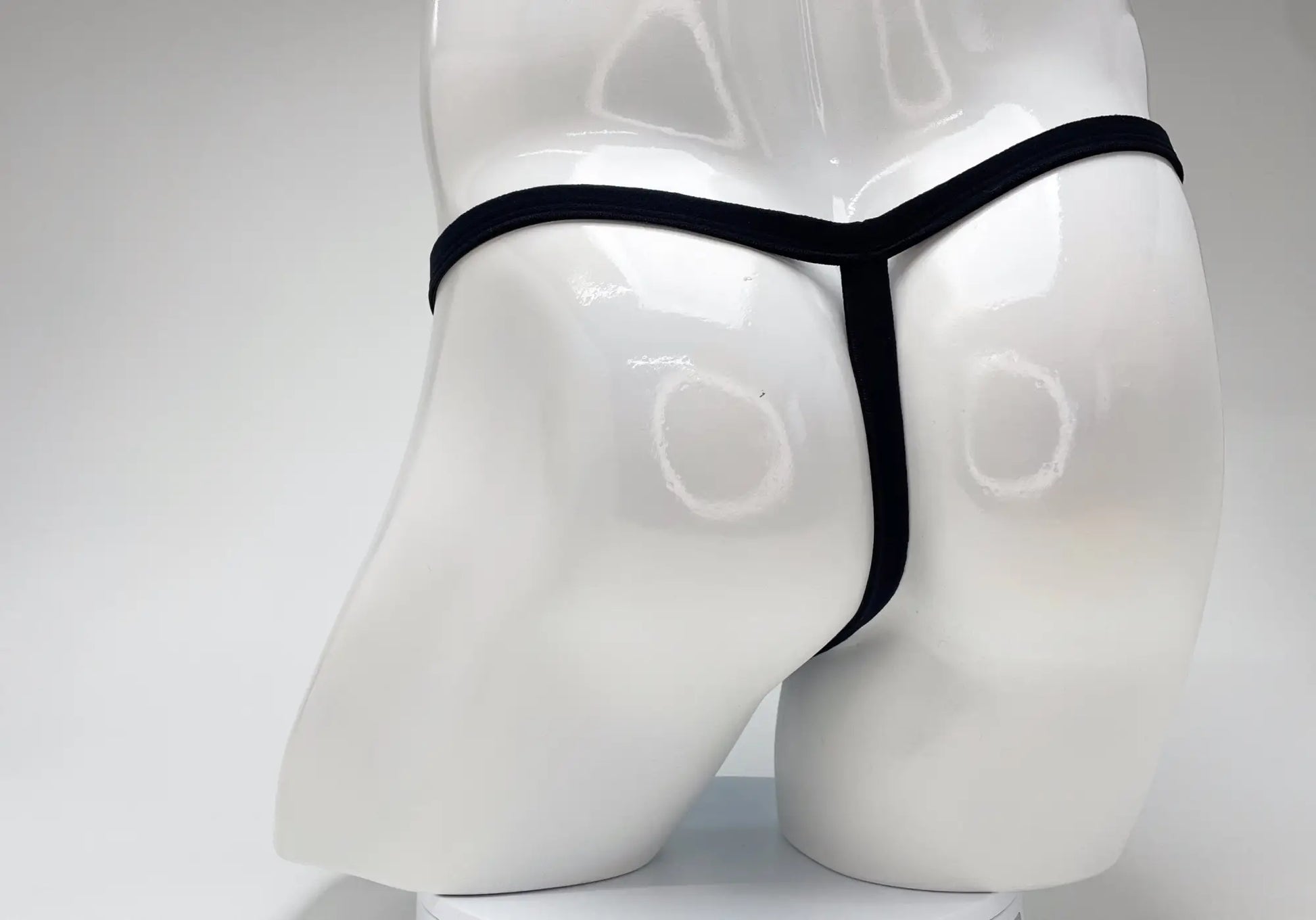Black thong displayed on white mannequin highlighting wildmant modal micro thong big boy pouch in baby blue color