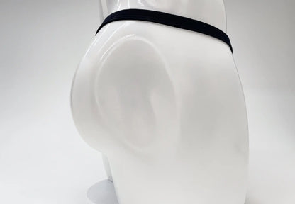 Back view of a gold-colored WildmanT micro thong on a white mannequin, featuring a thin black elastic waistband.