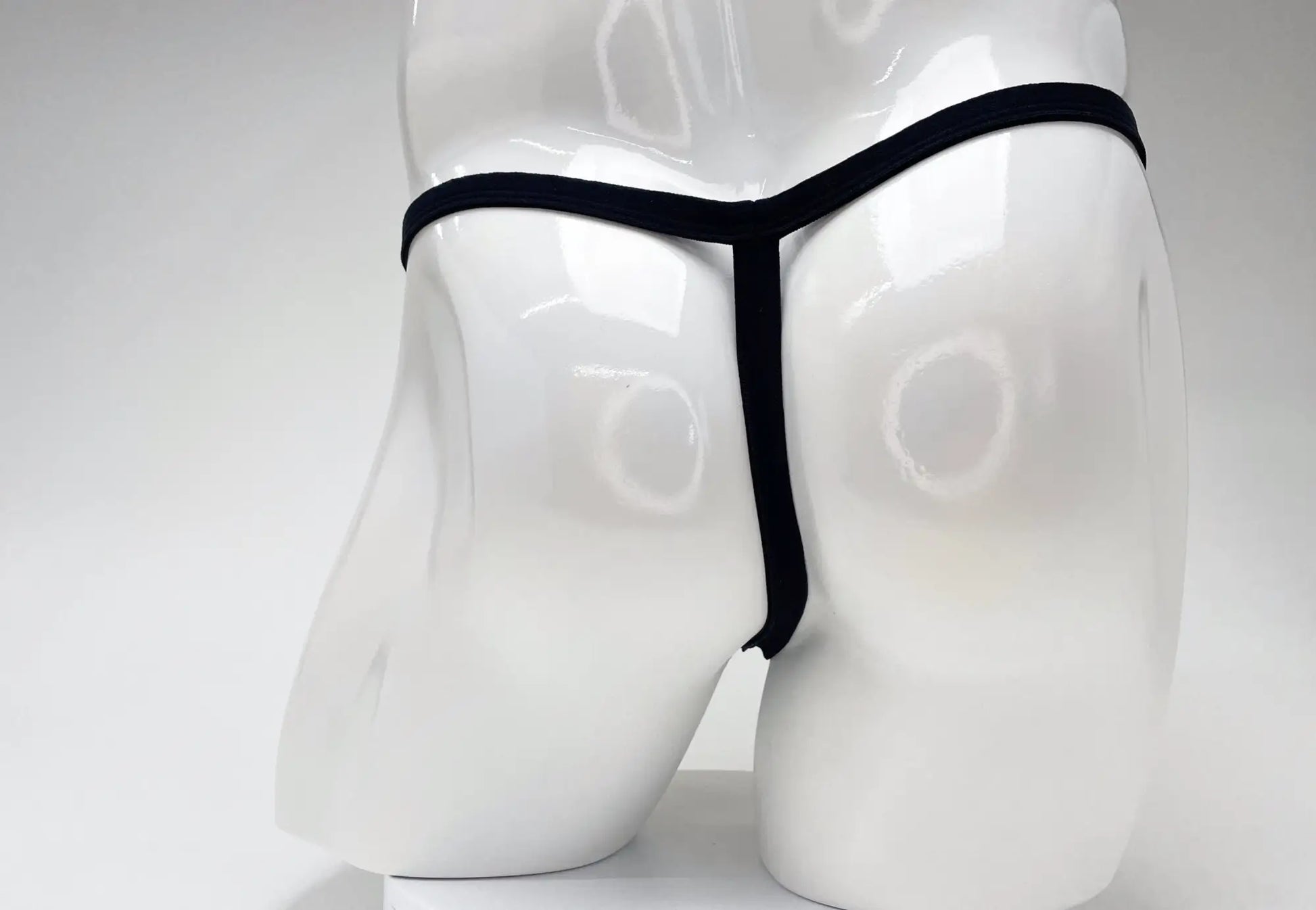 Back view of a white male mannequin wearing a minimalist black WildmanT modal micro thong.