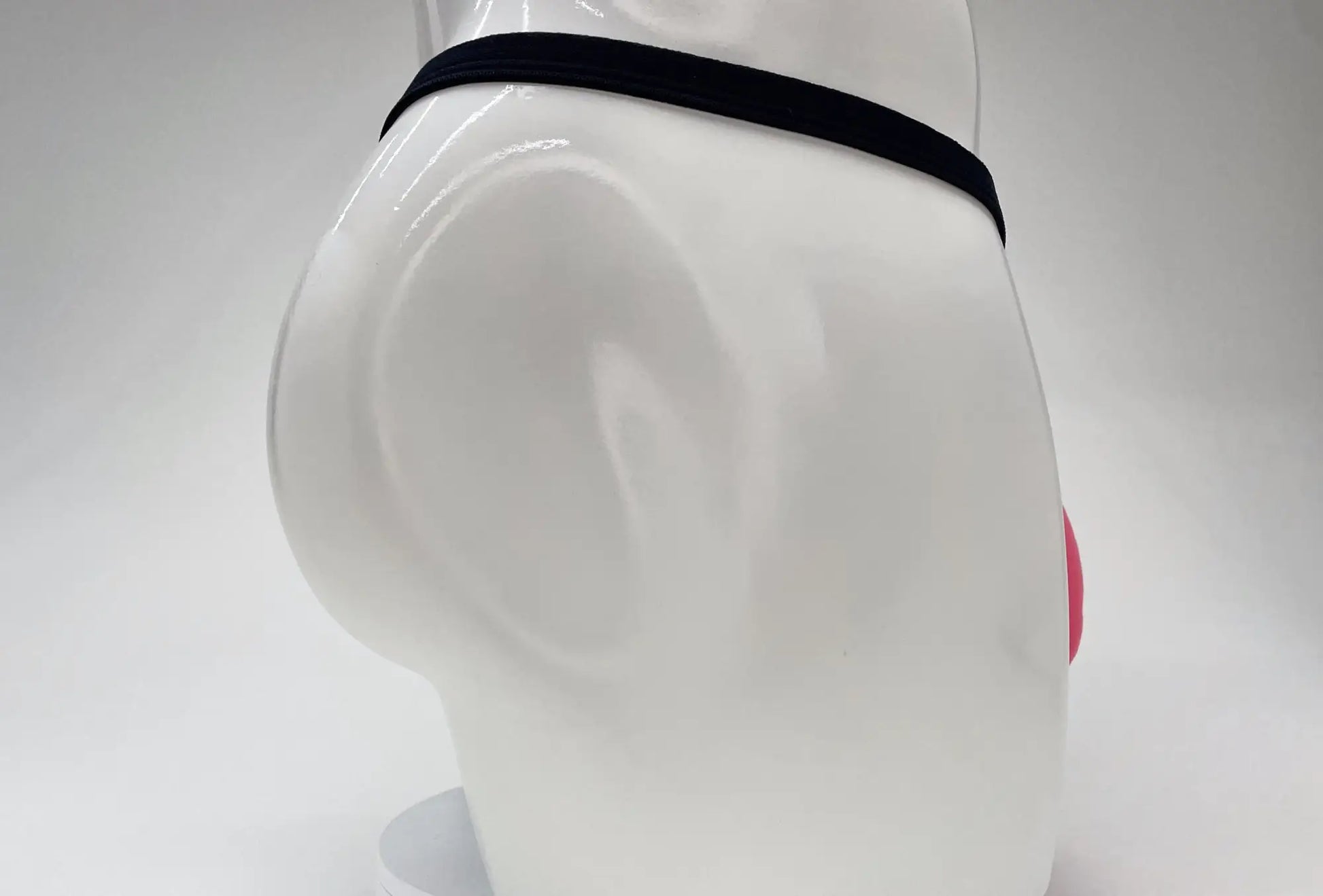 Pink WildmanT modal micro thong with a thin black waistband on a white mannequin torso.
