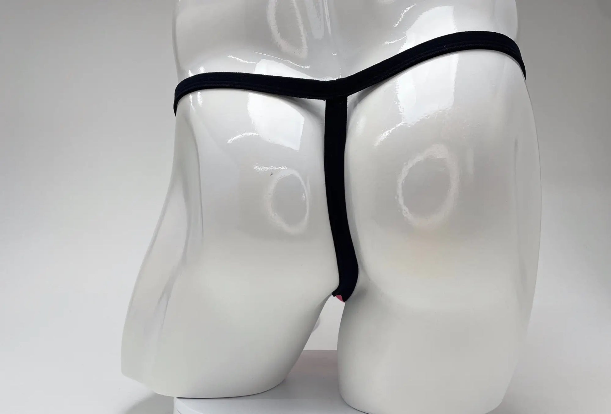Black thong with big boy pouch made of modal displayed on white mannequin for wildmant pink product line