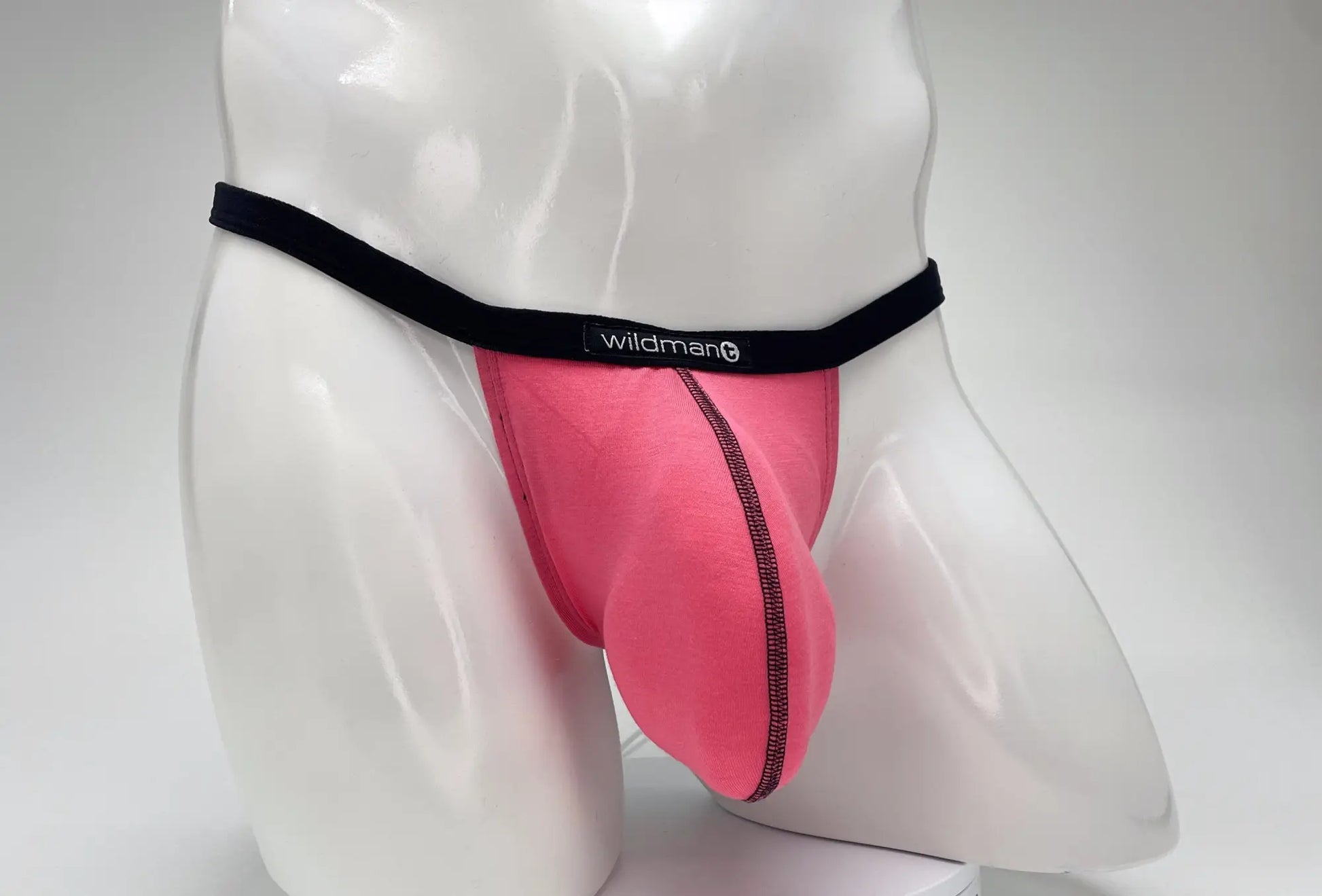 WildmanT pink modal micro thong with a prominent pouch, black waistband, and logo tag on a white mannequin torso.