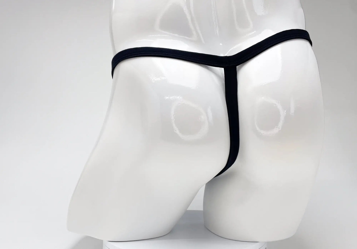 Back view of a purple WildmanT modal micro thong with a thin waistband on a glossy white mannequin torso.