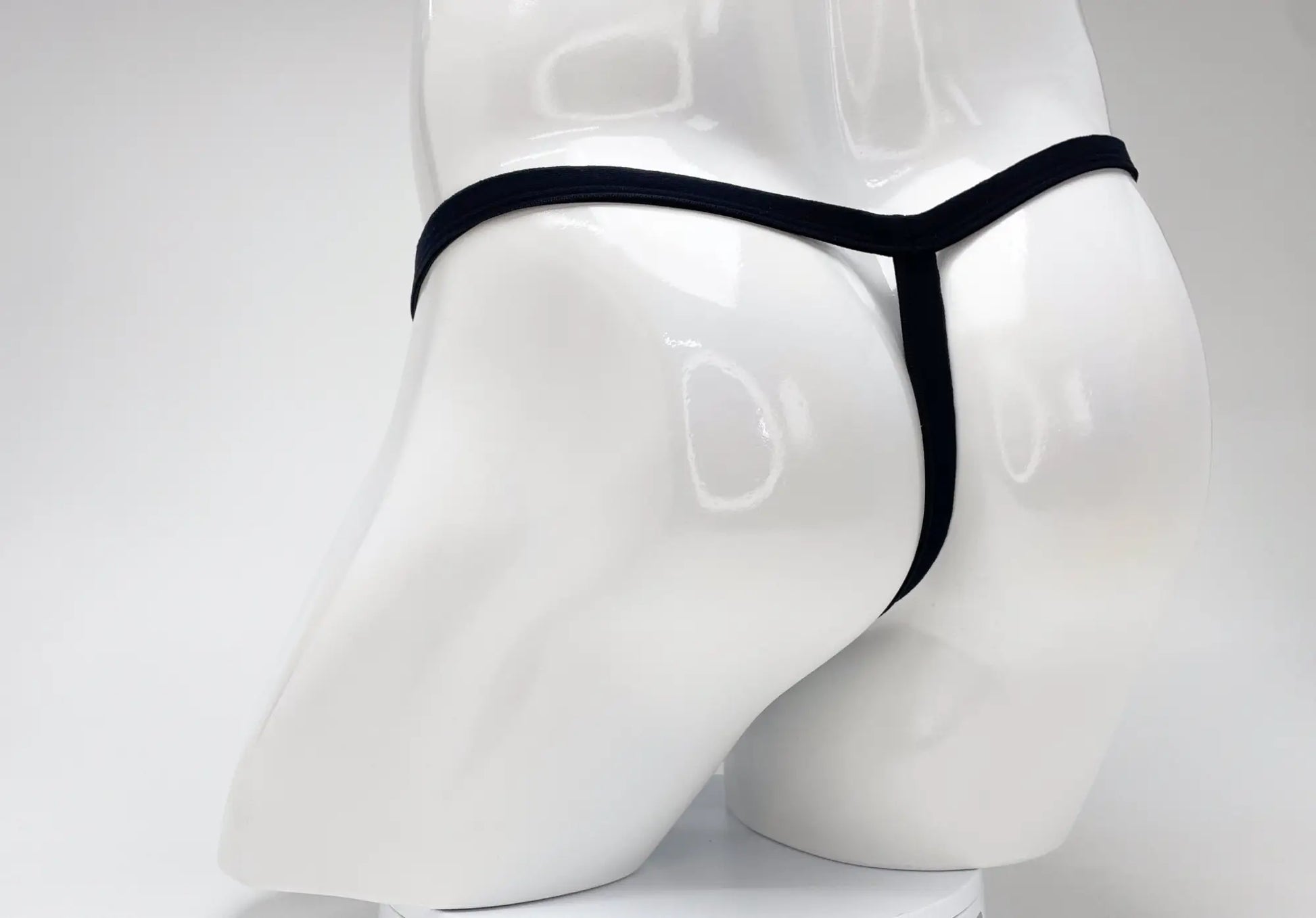 Black modal micro thong with big boy pouch displayed on white mannequin for wildmant purple product line