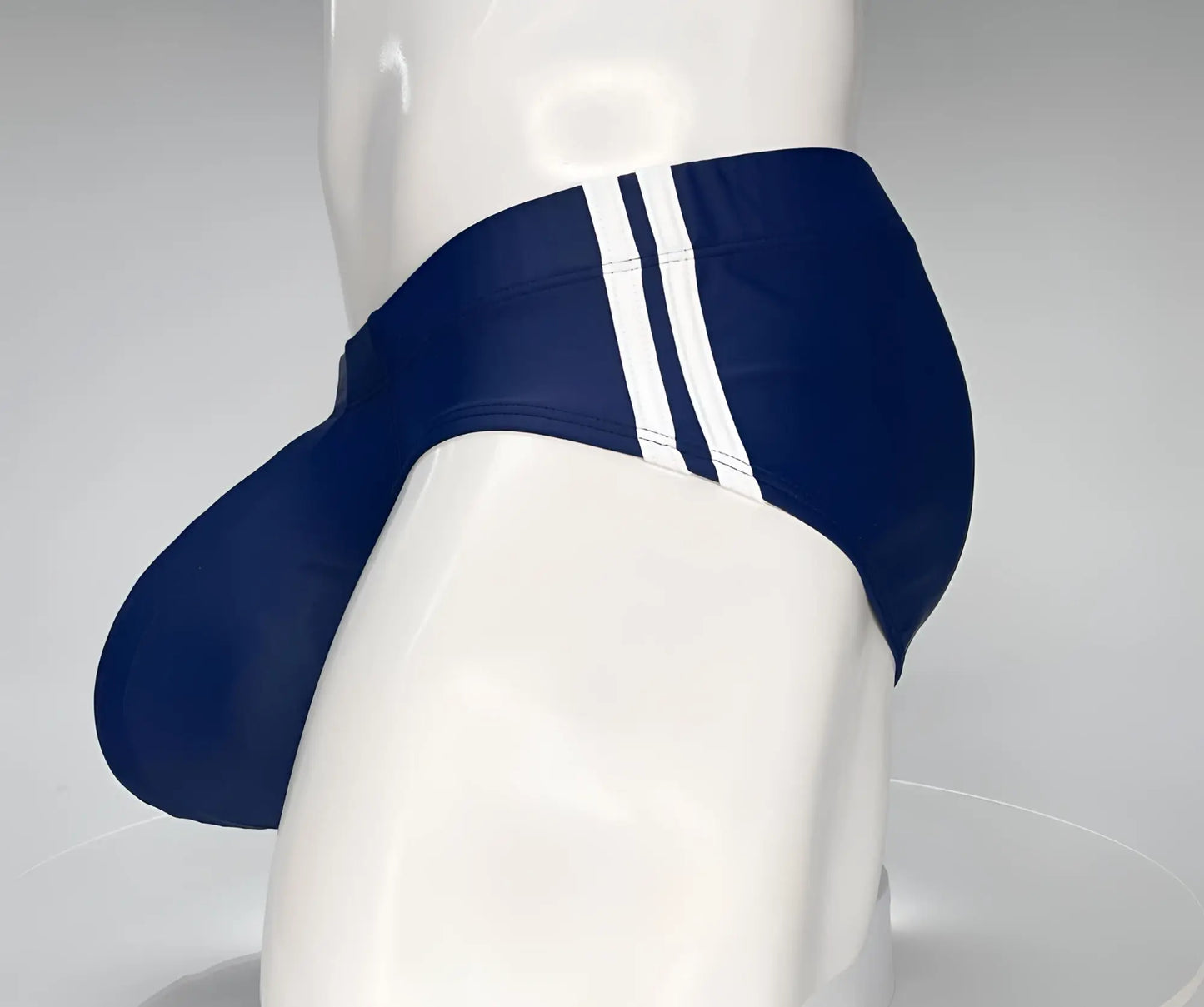 Wildmant monster cock swim brief navy blue swim trunks with three white side stripes displayed on mannequin