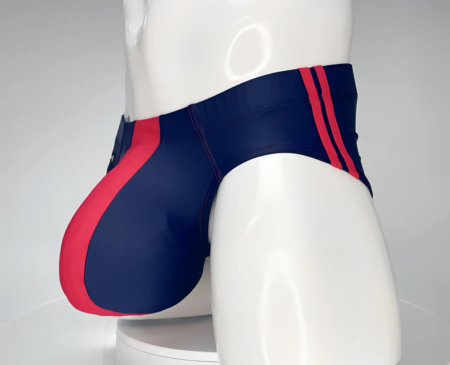 WildmanT monster cock swim brief in navy blue with bold red side panels and matching vertical waistband stripes