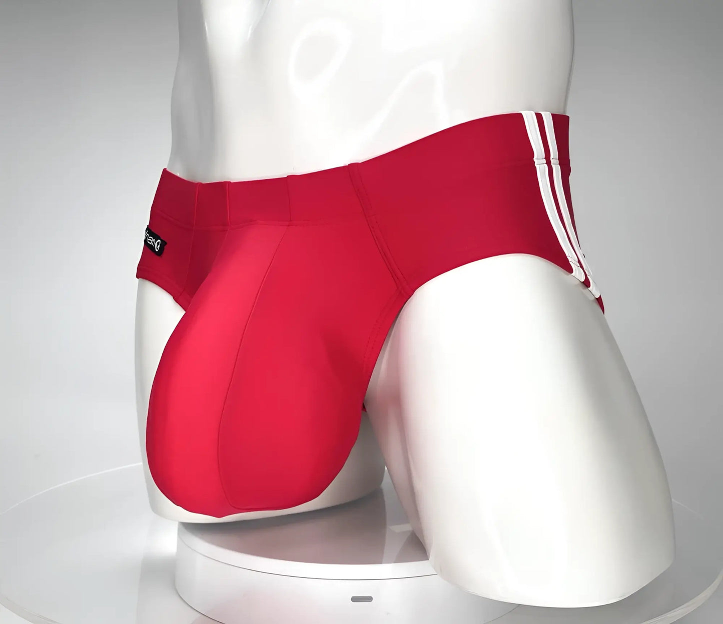 Wildmant monster cock swim brief red in red athletic fabric with white side stripes displayed on a mannequin front view