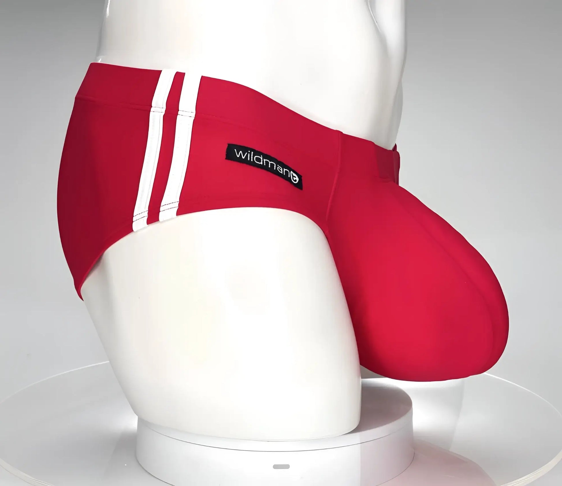 Red swim trunks with white side stripes and a black wildman brand label from wildmanT monster cock swim brief series