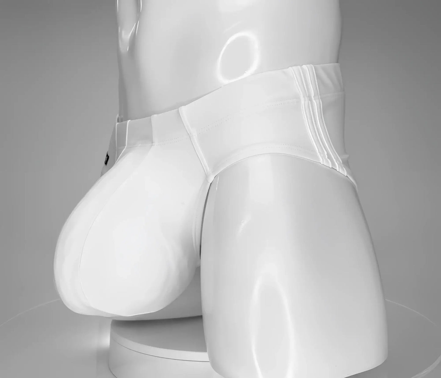 WildmanT monster cock swim brief white glossy latex briefs with smooth shiny surface and subtle vertical seam detailing