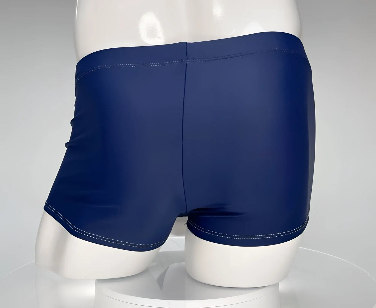 WildmanT navy blue square-cut swim trunks on a white mannequin, featuring a center seam and white contrast stitching.