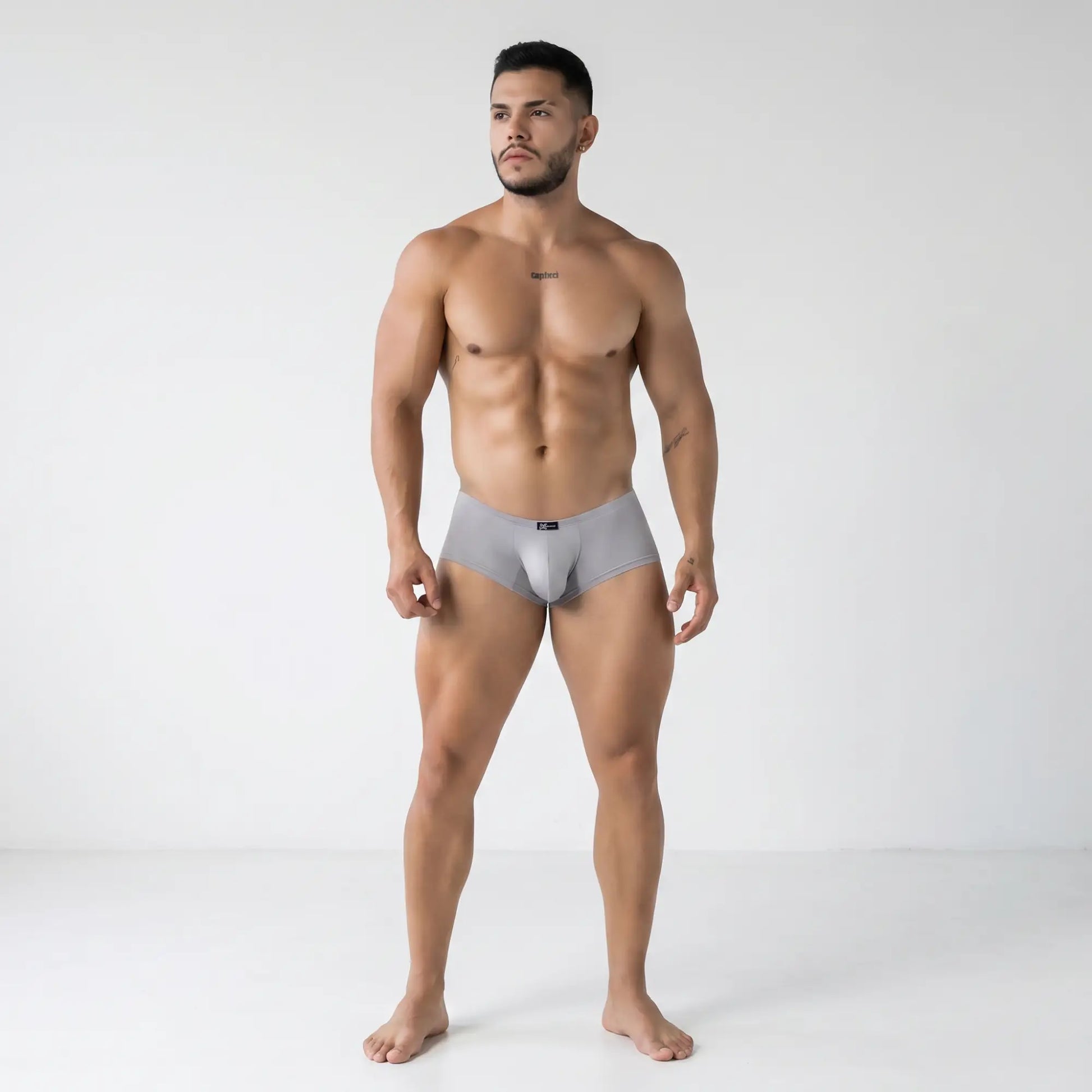 Athletic male model wearing Xtremen 91219 gray microfiber trunks in a minimalist studio, sleek form-fitting design