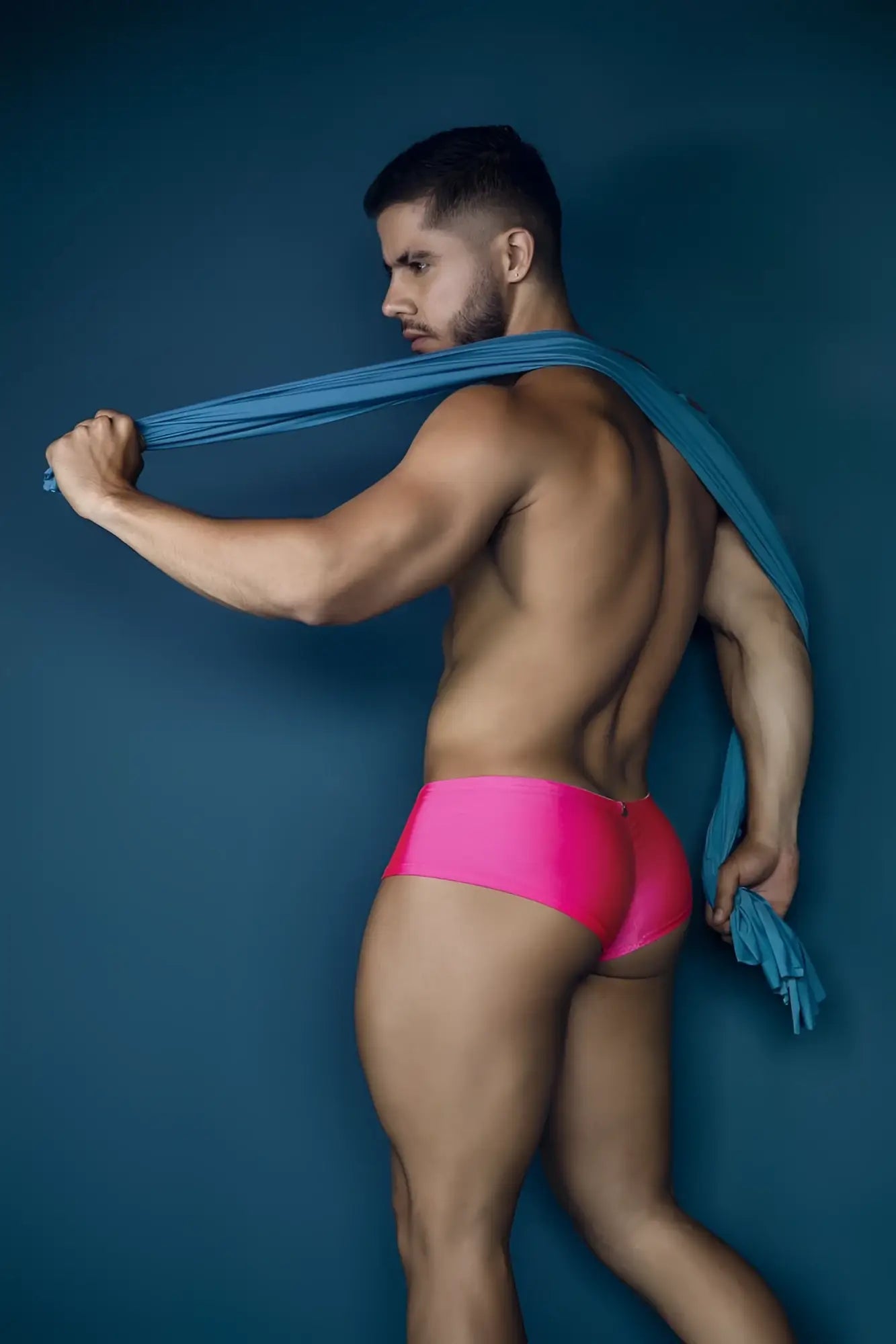 A man wearing xtremen 91234 microfiber trunks in fuchsia holding a blue fabric scarf over his shoulder