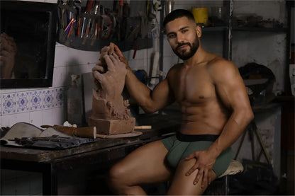 A clay sculpture of a hand being shaped by the artist wearing xtremen 91252 microfiber mesh trunks in military green