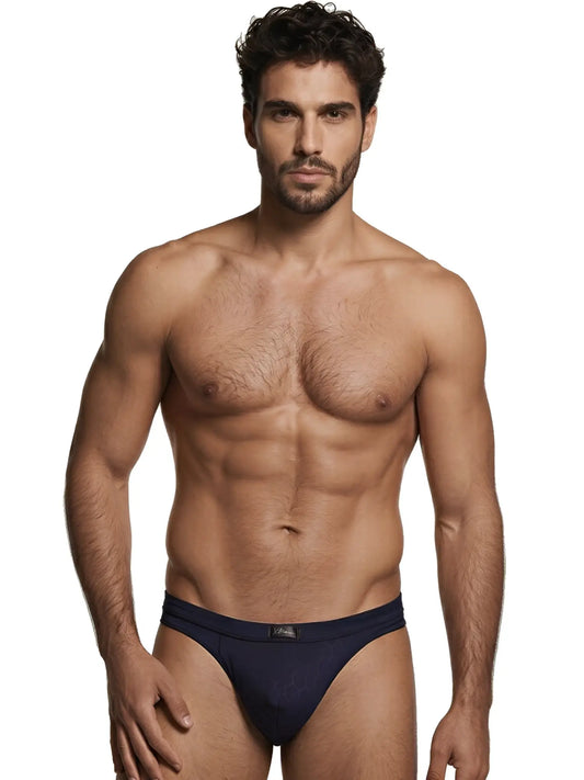 Xtremen navy blue bikini brief with a subtle geometric pattern and matte fabric finish worn by a fit male model.