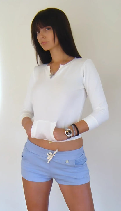White long-sleeved henley top with cropped hem paired with baby blue yoga training shorts for activewear