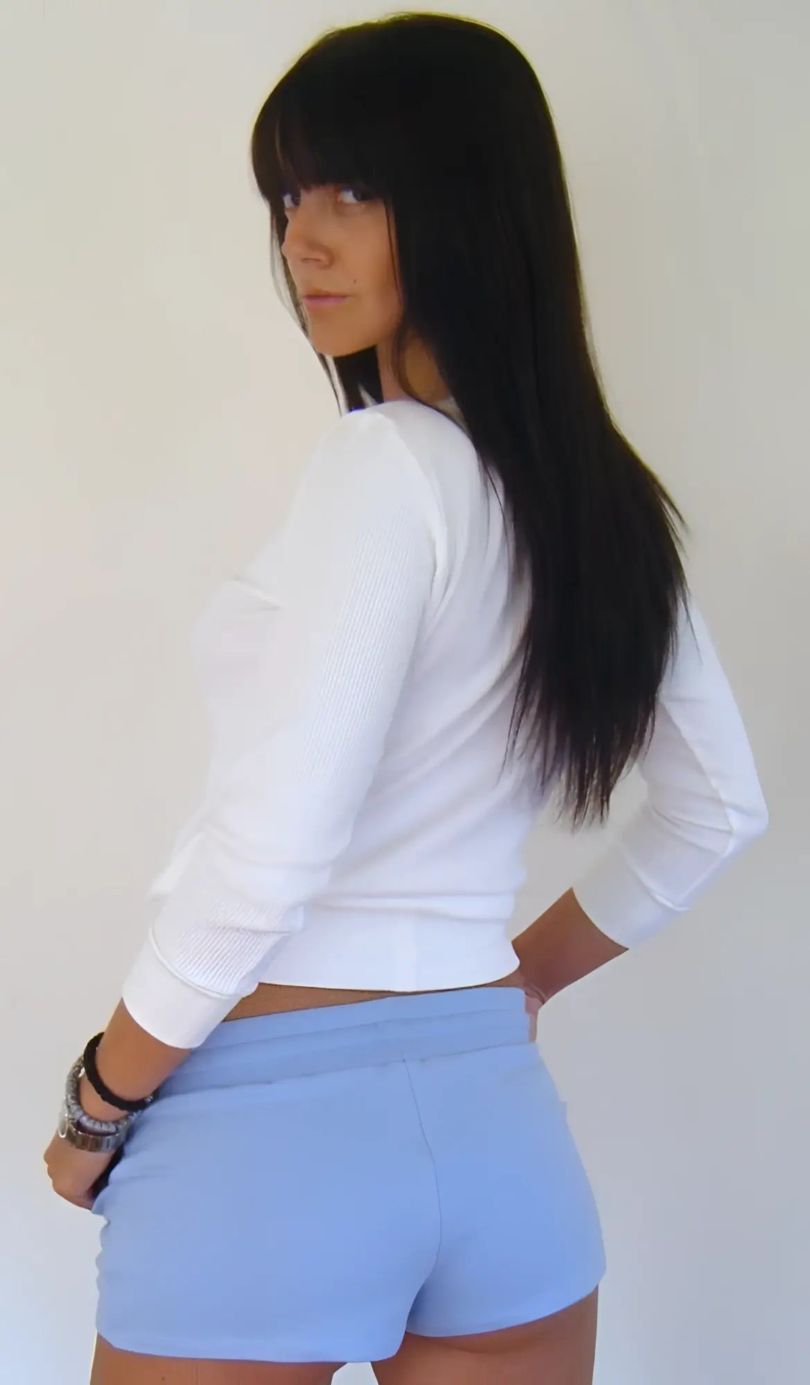 A woman wearing baby blue yoga training shorts and a white long-sleeved crop top shown from the front