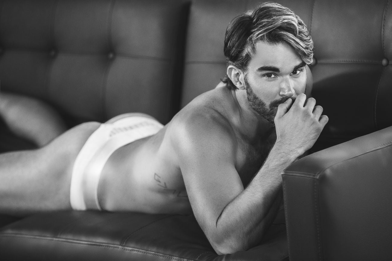 A man wearing white Clever 1034 Lucerna briefs lying on a couch showcasing the front fit and fabric detail
